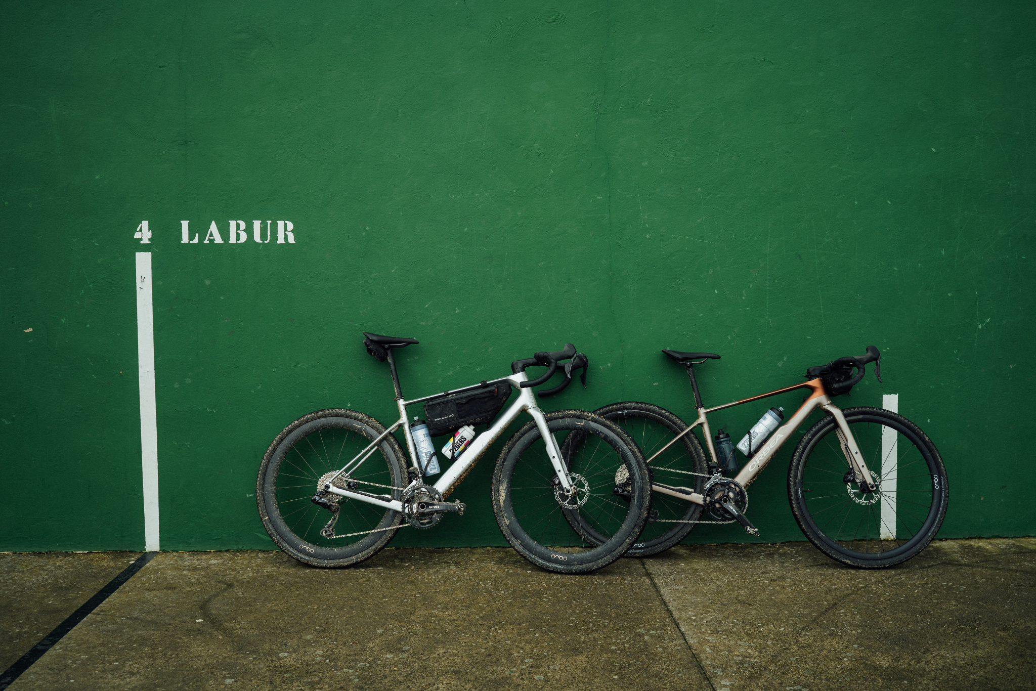 Zwei Gravelbikes vor einer grünen Wand